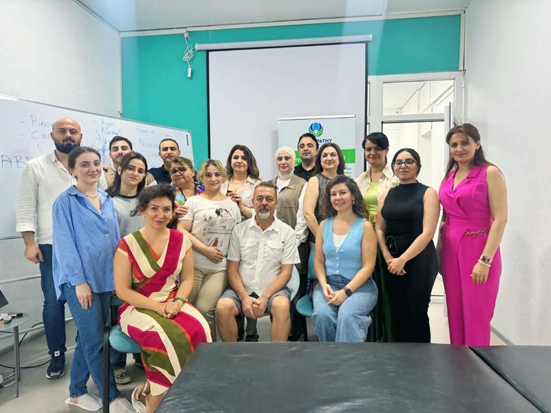 Tələbələr və müəllim ELF Center-in sinif otağında; önündə müalicə masası, arxada qeydlərlə dolu yazı lövhəsi.